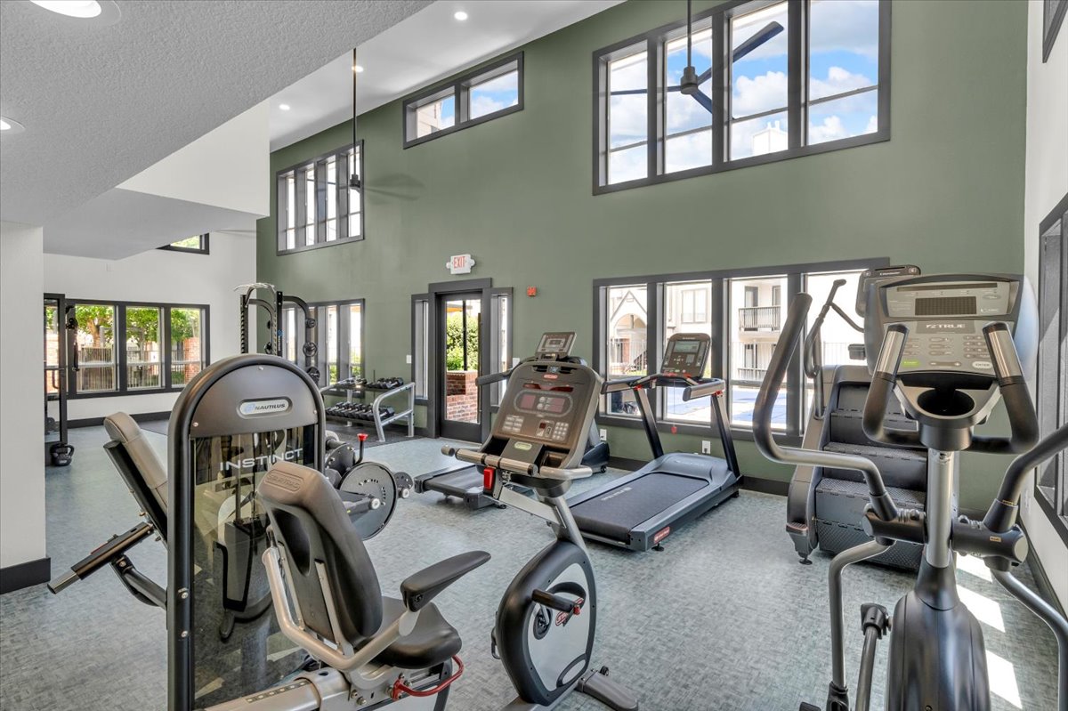 a gym room with exercise equipment and windows at The Residences at Bear Creek