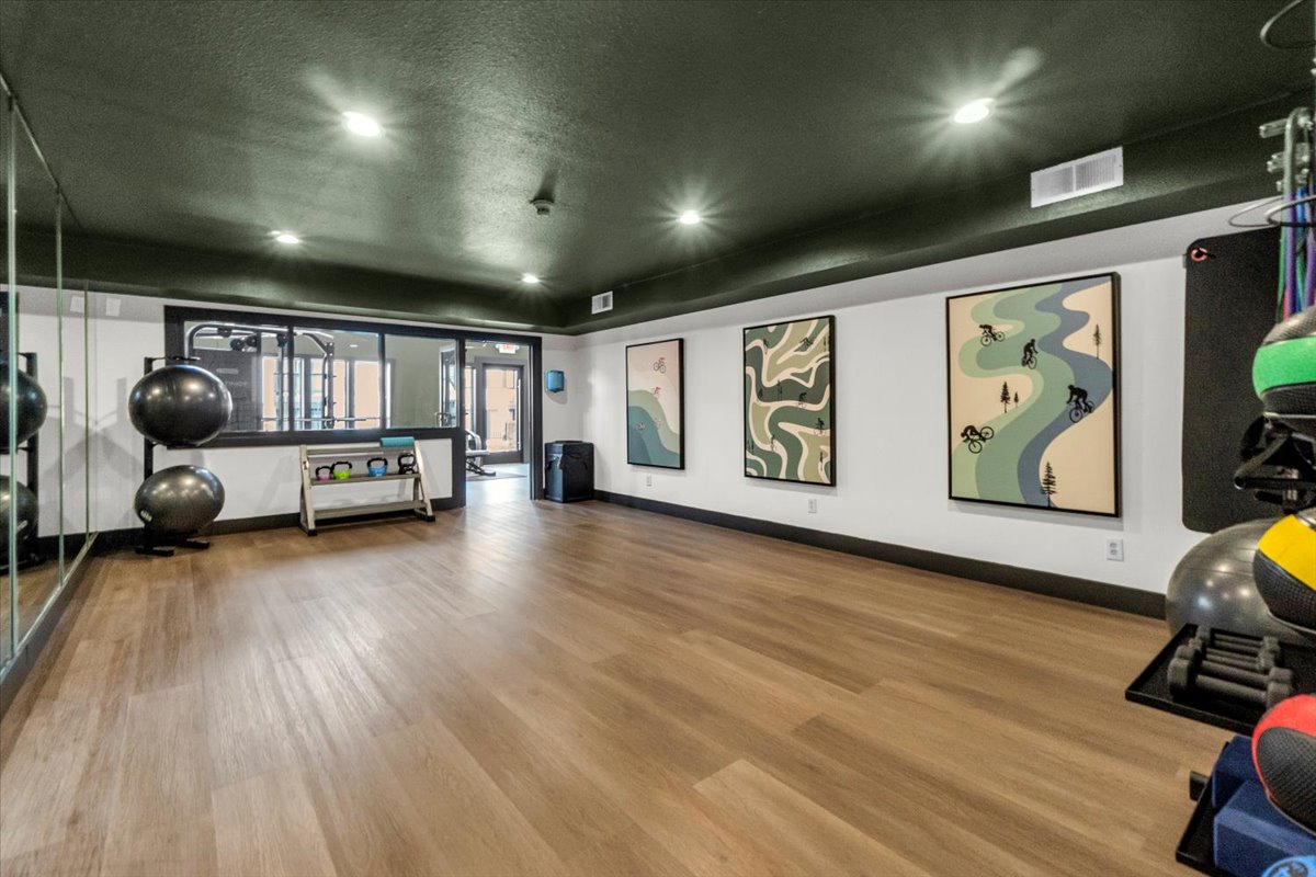 a gym room with a large mirror and wood floors at The Residences at Bear Creek